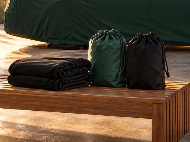 Two storage cases, one green and one black, beside two folded covers on a bench