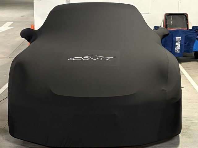 The Covr Indoor cover fitted to a car in an underground carpark, seen from the front with the logo on the bonnet